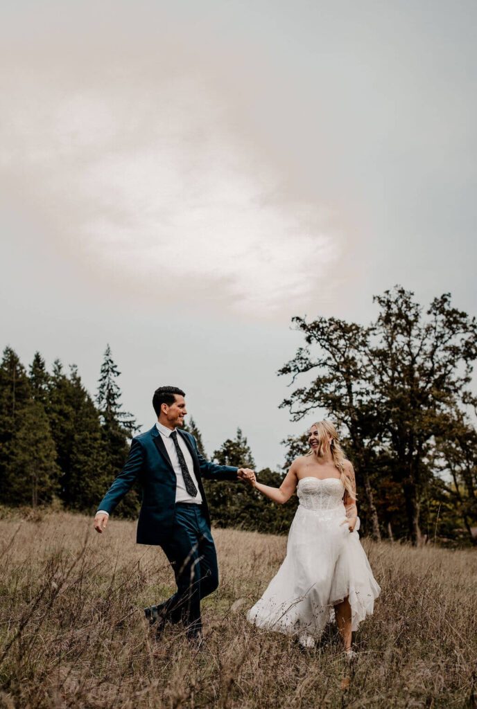 Oregon bride and groom run through a field during sunset at Mt. Pisgah