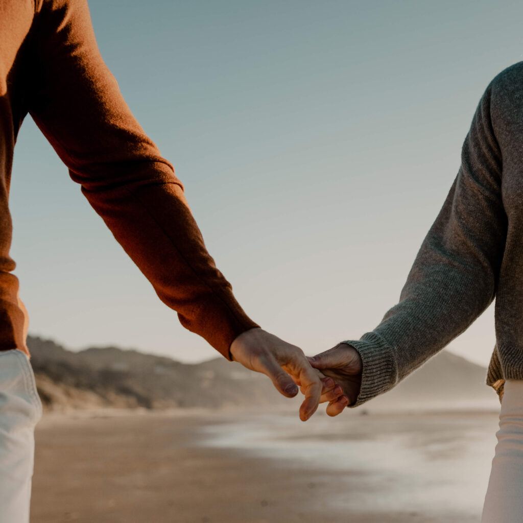 Couple holds hands at an oregon coast beach engagement session