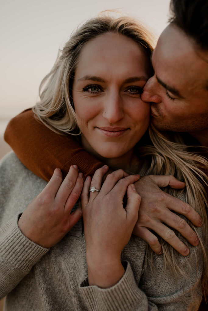 Groom kisses his bride at an oregon coast engagement photo session