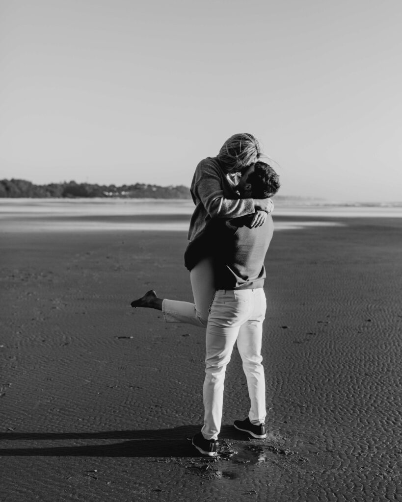 Groom holds his bride on the beach for an oregon coast engagement session