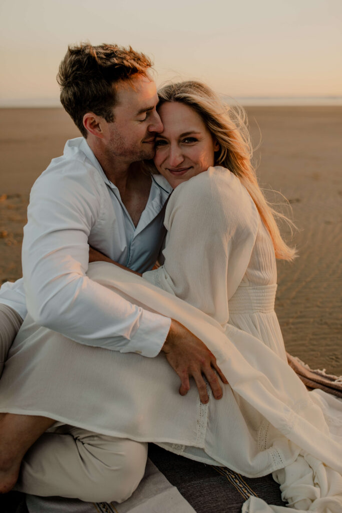 Couple cuddles on the beach for an oregon coast engagement session