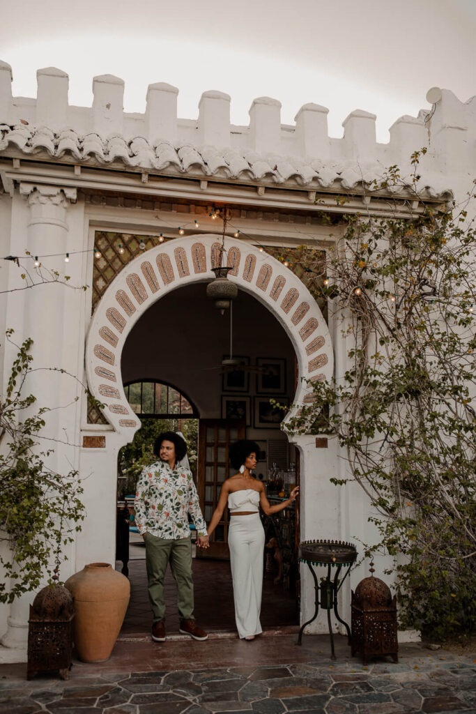 Bride and groom stand in front of Korakia Pensione archway in palm springs