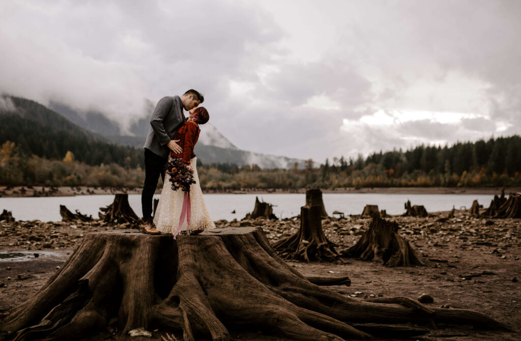 Couple stand on a tree stump at a Washington Elopement on Rattlesnake Ledge