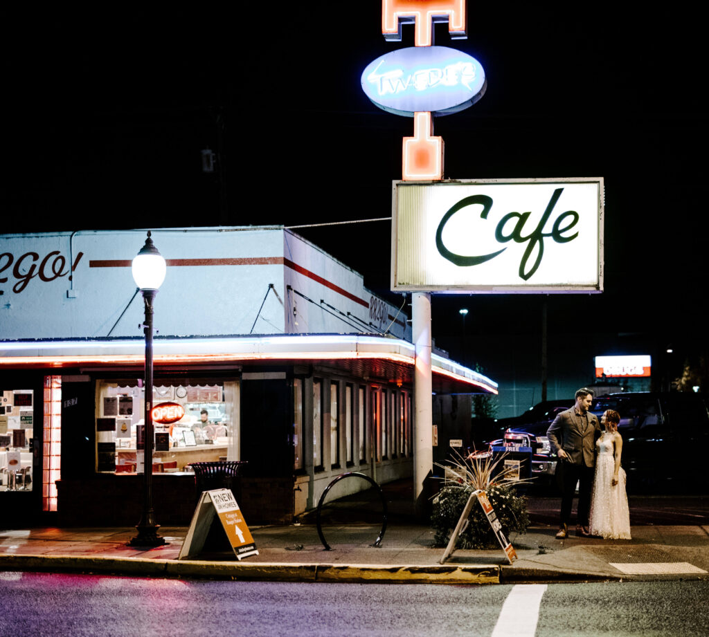 Couple poses in front of a diner at a Washington Elopement on Rattlesnake Ledge