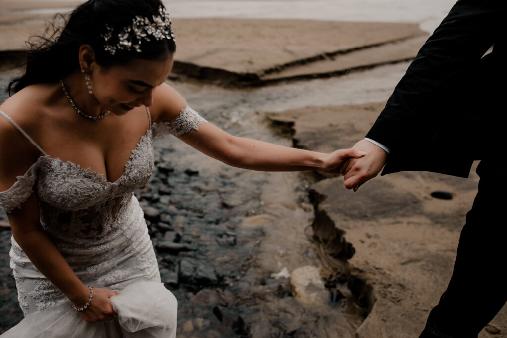 Couple holds hands under a cave at their hug point oregon elopement