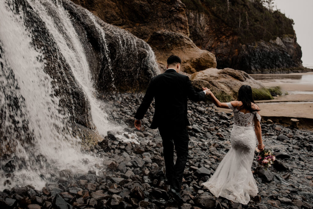 Couple walks next to the Hug point waterfall at their elopement