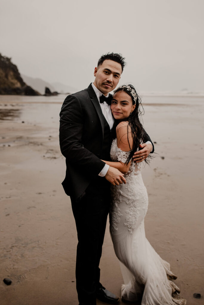 Couple poses at a hug point elopement on the beach