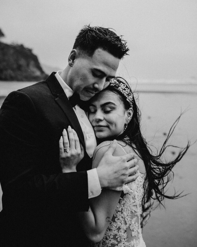 Couple hugs on a beach at Hug Point in Oregon at their elopement