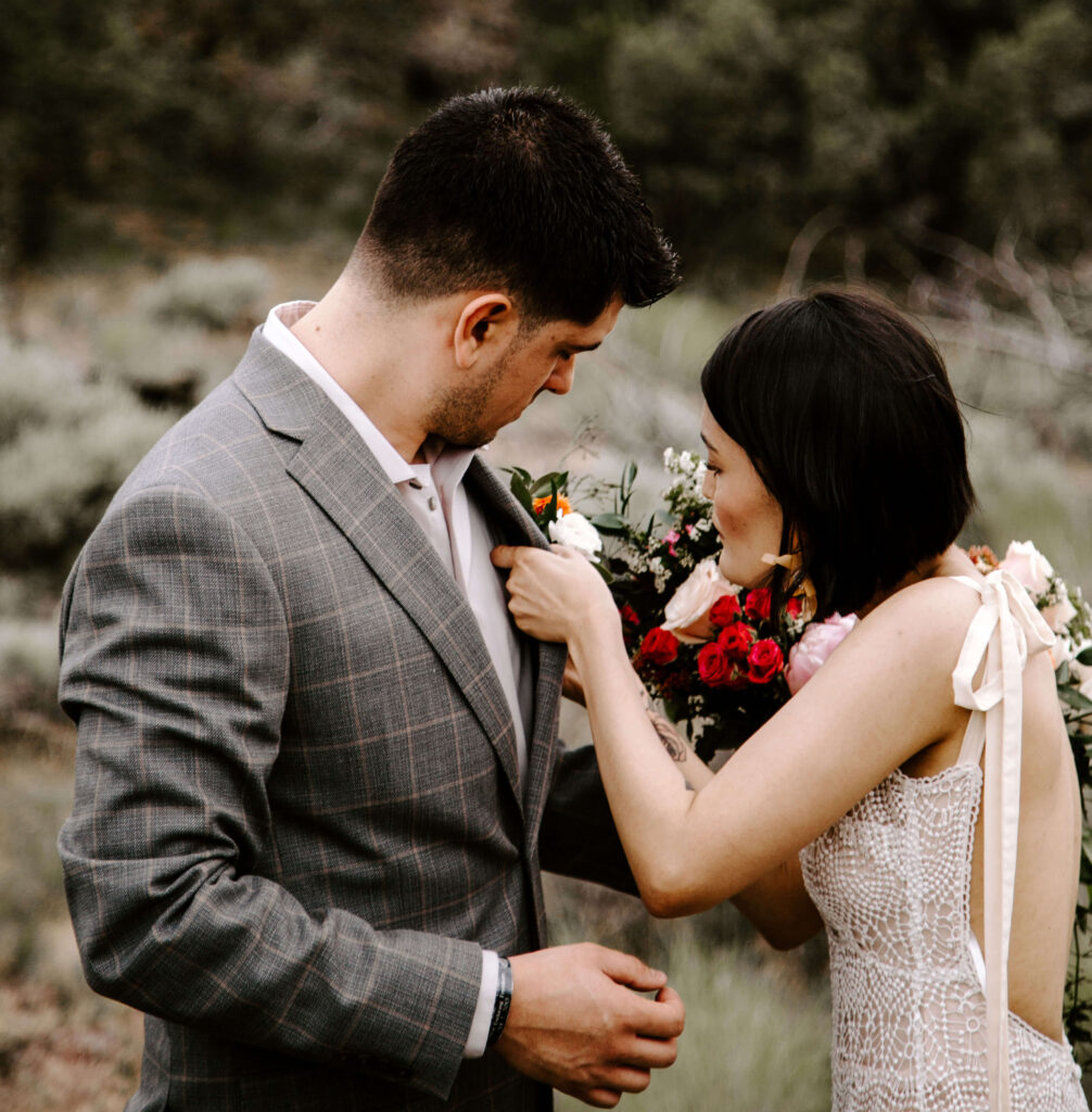 Bride pins flowers to her groom at a smith rock elopement