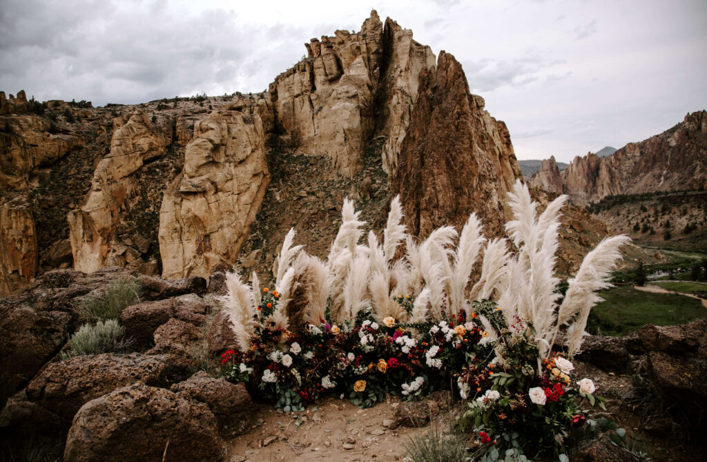 Florals and pampas grass in front of the cliffs at Smith Rock in Oregon