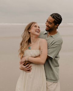 Couple laughs on the beach at an Oregon coast engagement session shot by Ronny and Rene.