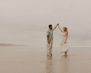 Couple dances on the beach at an Oregon coast engagement session shot by Ronny and Rene.