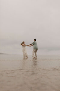 Couple runs on the beach at an Oregon coast engagement session shot by Ronny and Rene.