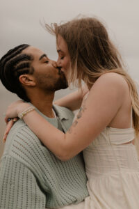 Couple kisses on the beach at an Oregon coast engagement session shot by Ronny and Rene.