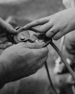 couple showcasing engagement ring with hiking gear