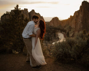 couple kissing with rock landscape and river behind at smith rock elopement photoshoot