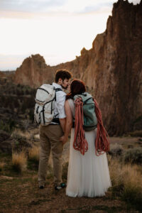couple kissing with hiking backpacks at smith rock engagement photoshoot