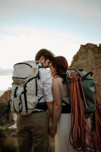 couple with foreheads pressed together and hiking backpacks engagement photoshoot
