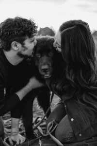 couple kissing dog from both sides engagement shoot