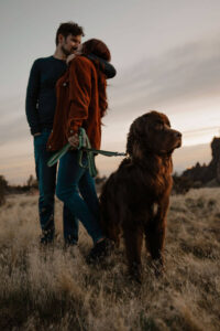 couple kissing with dog in frame engagement photoshoot