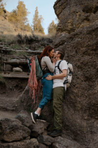 couple hiking together at smith rock kissing with hiking equipment