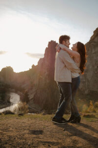 couple hugging and looking at each other at smith rock with landscape behind