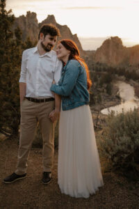 wife rests head on husband as he looks at her with smith rock landscape behind them elopement photoshoot