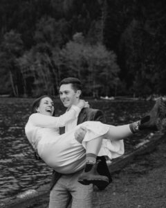 groom carries bride in arms alone olympic national park lake