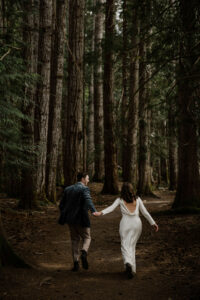 wedding couple hold hands in olympic national park forest