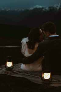 elopement couple at olympic national park mountain with snow and lanterns at night sitting on blanket