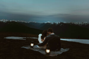elopement couple at olympic national park mountain with snow and lanterns at night sitting on blanket