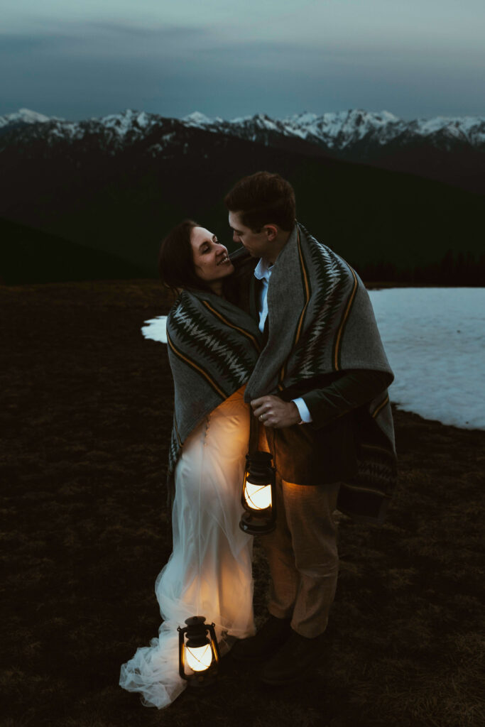 elopement couple at olympic national park mountain with snow and lanterns at night wrapped together with blanket