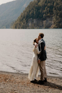 wedding couple hugging in front of lake at olympic national park