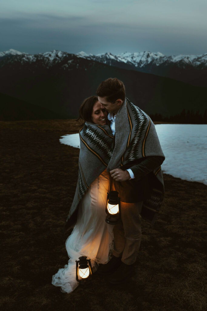elopement couple at olympic national park mountain with snow and lanterns at night wrapped together with blanket