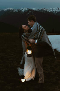 elopement couple at olympic national park mountain with snow and lanterns at night wrapped together with blanket