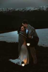 elopement couple at olympic national park mountain with snow and lanterns at night wrapped together with blanket
