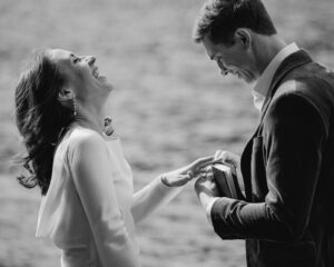 wedding couple putting rings on each other in front of lake at olympic national park