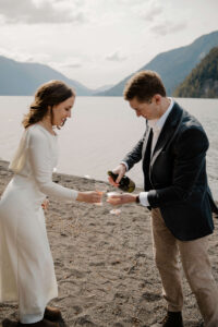 elopement couple at olympic national park lake pouring champagne