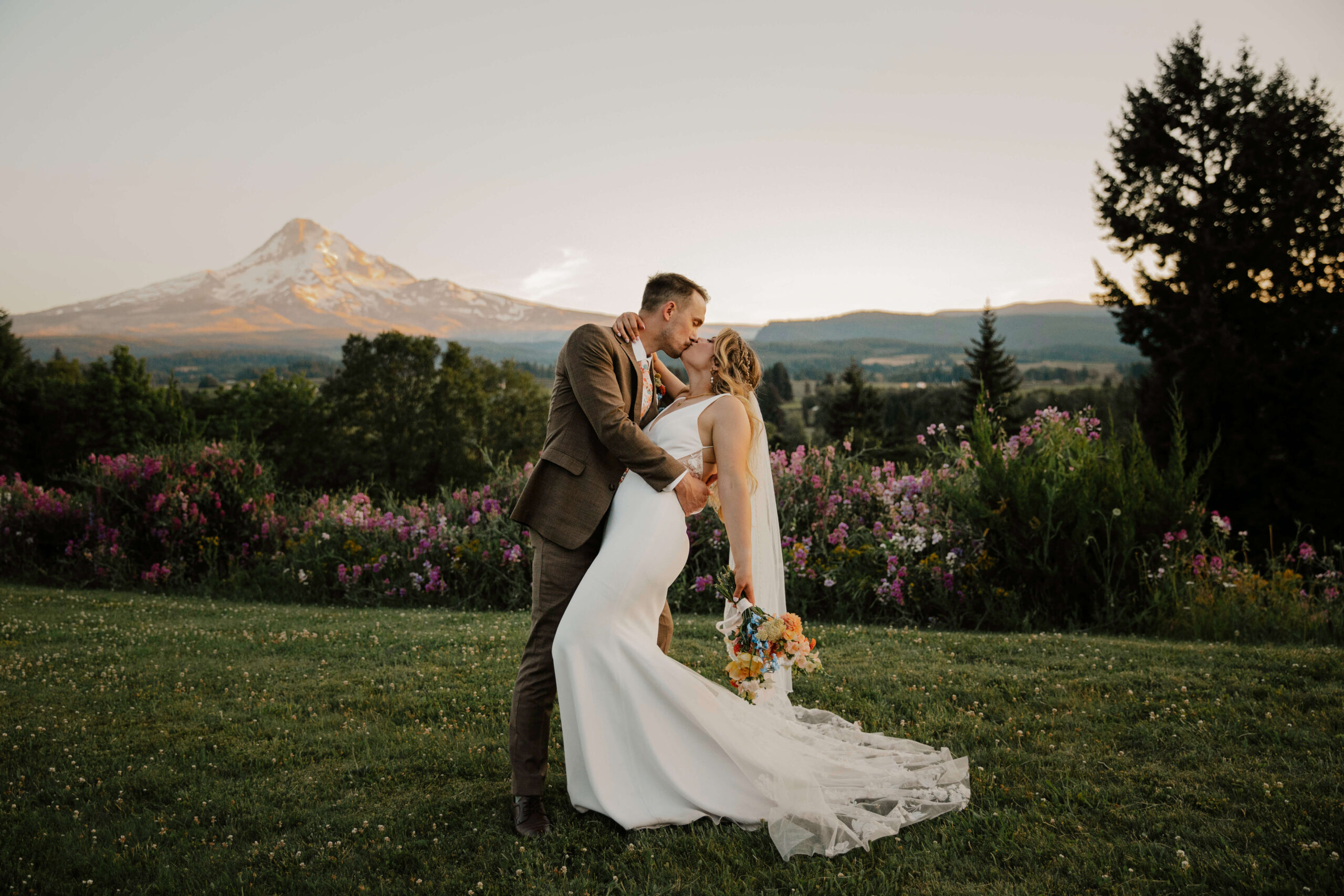 Couple kisses and leans into a dip in front of mount hood.