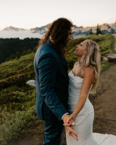 couple holds hands looking at each other during mount rainier hike after eloping
