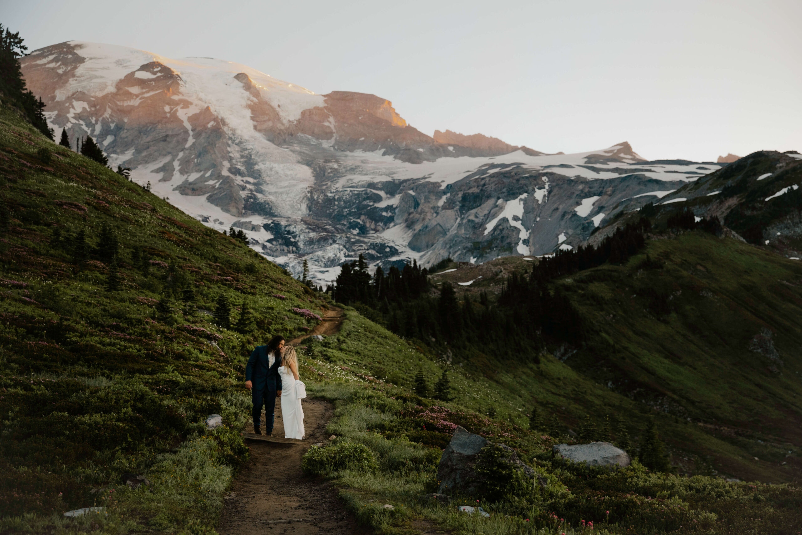 couple kisses in wedding dress and suit in mount rainier elopement hike with landscape