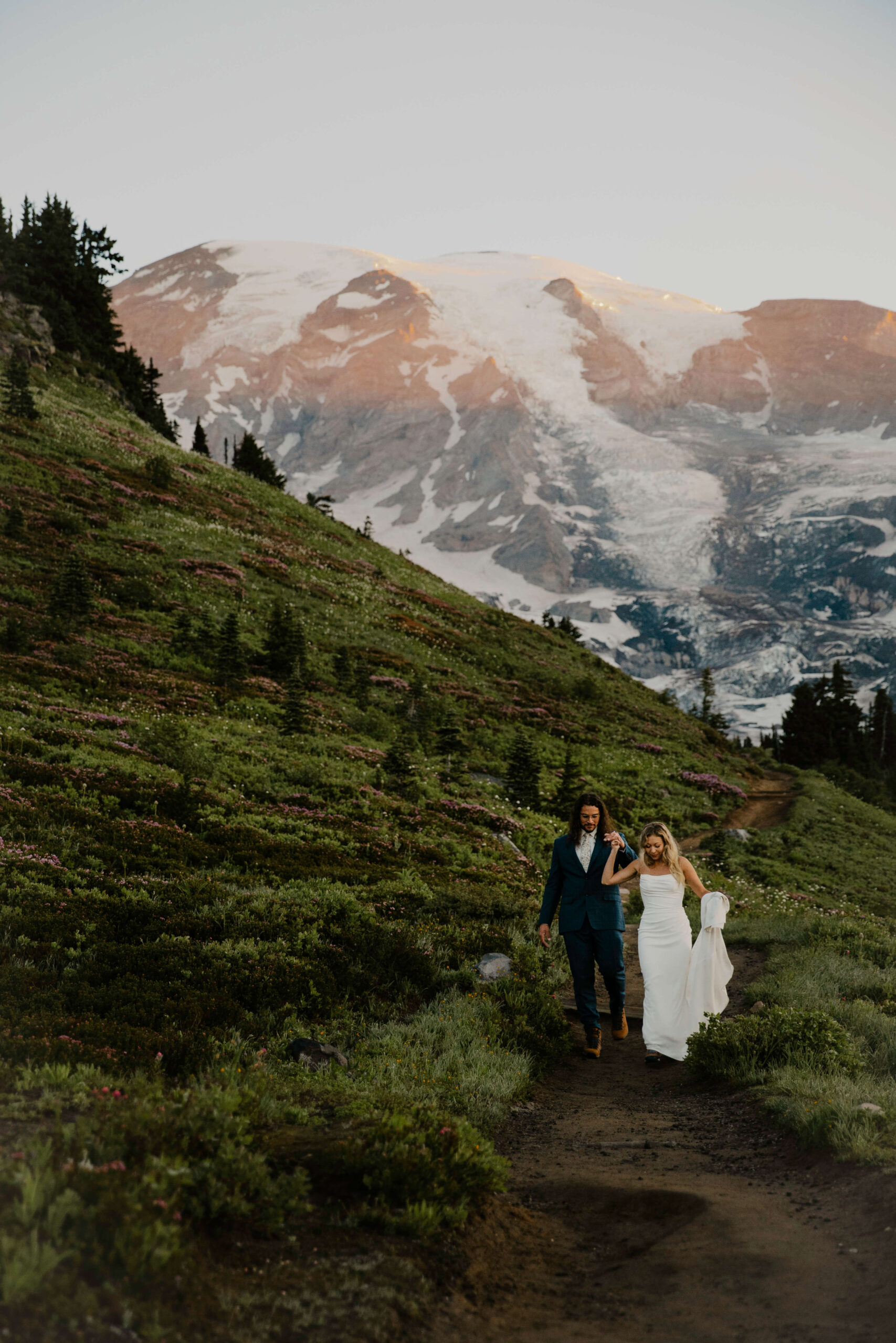 couple hold hands hiking after their wedding ceremony at mount rainier
