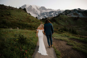 couple holds hands as they walk together on mount rainier hike elopement