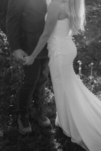 an outfit photo of the bride and the groom and his hiking shoes and her wedding dress