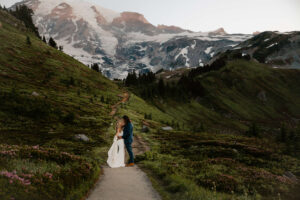 couple looks into each others eyes on mount rainier hike with beautiful landscape behind them after elopement
