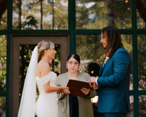 elopement bride and groom look into each other's eyes while officiant reads to them at mount rainier cabin elopement ceremony