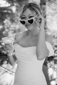 portrait of elopement bride wearing decorated glasses and drinking a margarita in black and white at mount rainier elopement