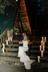 Couple sitting on stairs in candlelit mount rainier cabin in wedding dress and tux