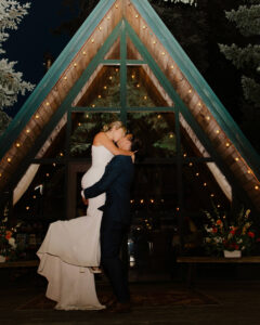 Groom holds bride up in arms while kissing at Mount Rainier Cabin Elopement Ceremony