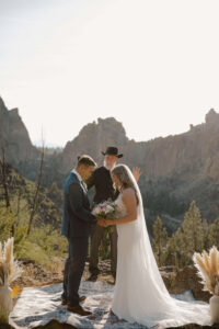 Couple exchanging vows with mountain peaks in the distance.